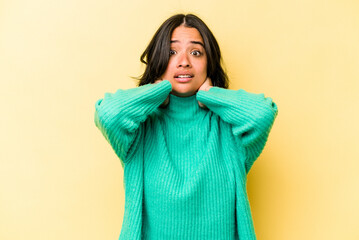 Young hispanic woman isolated on yellow background screaming with rage.