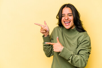 Young hispanic woman isolated on yellow background pointing with forefingers to a copy space,...