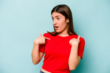 Fototapeta premium Young caucasian woman isolated on blue background surprised pointing with finger, smiling broadly.