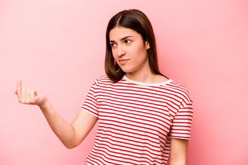 Young caucasian woman isolated on pink background pointing with finger at you as if inviting come closer.