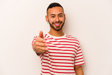 Fototapeta premium Young hispanic man isolated on white background stretching hand at camera in greeting gesture.