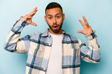 Naklejka premium Young hispanic man isolated on blue background celebrating a victory or success, he is surprised and shocked.