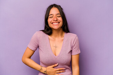 Fototapeta premium Young hispanic woman isolated on purple background touches tummy, smiles gently, eating and satisfaction concept.