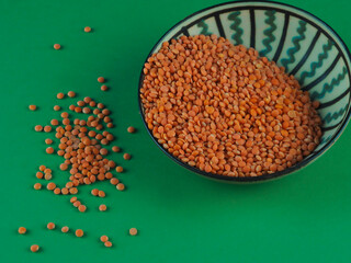 Red lentils in a green bowl on a green background. Red lentils macro