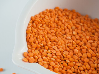 Red lentils in a white bowl on a white background. Red lentils macro