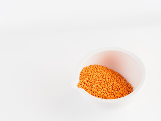 Red lentils in a white bowl on a white background. Red lentils macro