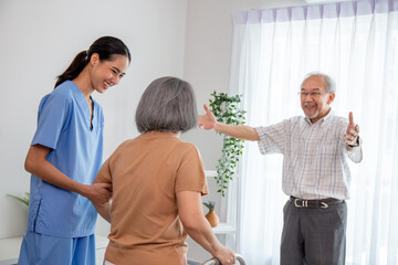 Asian young nurse take care a senior with a walker in a retired home service.