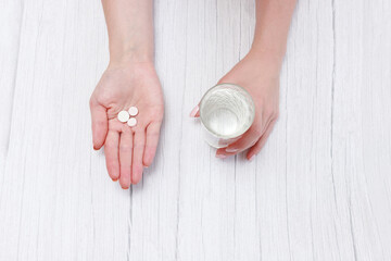 group of tablets in hand and glass of water. Top view
