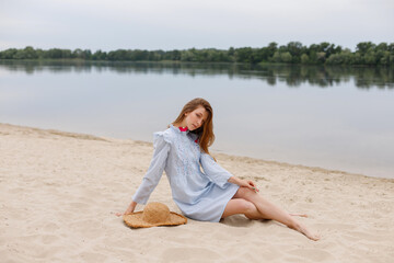 an attractive woman with a straw hat on the riverbank in the summer. summer mood