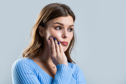 Toothache, Woman with Tooth Infection. Woman suffering from toothache against gray background. Young woman suffering from toothache. Girl suffering from toothache, tooth decay or sensitivity