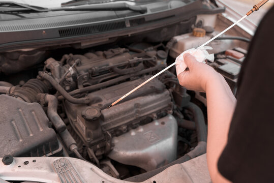 A woman's hands checking the oil level of a car with an oil dipstick.