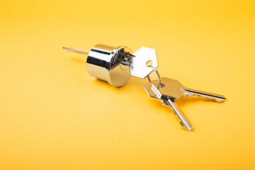 New door lock on a yellow background. Patent and keys from the front door. Contact tumbler of the internal mechanism of the cylinder lock and a set of keys. Real estate concept