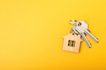 House keys with a keychain in the shape of a house.Composition on a yellow background.Design...