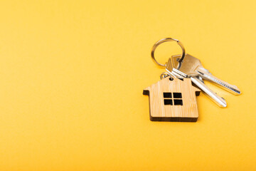House keys with a keychain in the shape of a house.Composition on a yellow background.Design element.Real estate and insurance concept.Copy space.