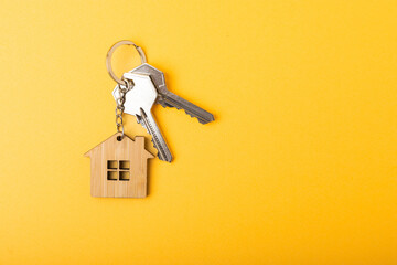 House keys with a keychain in the shape of a house.Composition on a yellow background.Design...