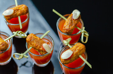 Bloody Mary cocktails in the shots drink served with Halloween bloody fingers, pork cocktail sausages decorated with flaked almonds