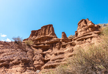 Fototapeta premium Red tales from clay. Issyk-Kul region in Kyrgyzstan. Beautiful mountain landscape. Tourism and travel.