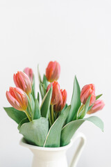 Bouquet of delicate pink tulips in a jug.