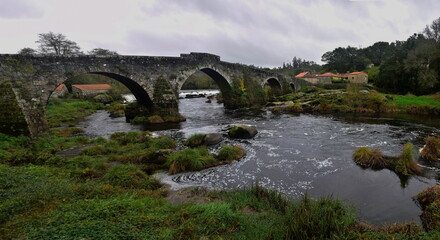 Fototapeta na wymiar Old stone bridge with arches across the river. The Way of St. James, Northern Route, Spain.