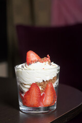 Dessert of strawberries with cream. In a glass jar. Close-up.