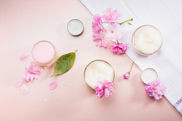 Obraz na płótnie Canvas Body care cream and pink cherry blossoms.