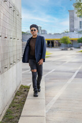 Latin gay male with makeup wearing fashion hat doing catwalk in the street
