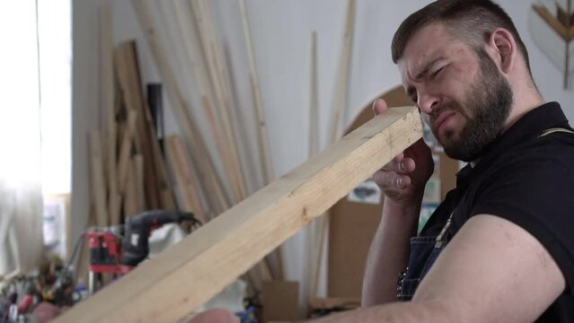 Portrait of an adult male carpenter in a carpentry workshop, slow motion. The carpenter works with wood