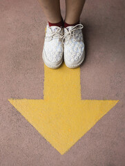 Feet and arrows on road. Yellow straight arrow sign and white shoes. Straight direction concept....