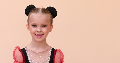 Portrait of beautiful gymnastics girl with make up and hair dressing posing on beige background. Copy space