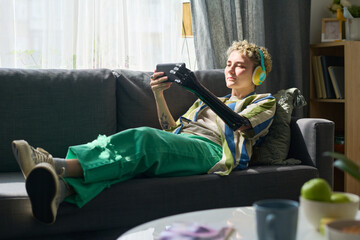 Girl with disability in headphones watching online movie in smartphone or communicating in video...