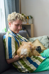 Happy girl with physical disability playing with cute purebred dog while relaxing on comfortable...
