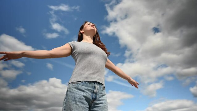 Caucasian woman spread her arms like wings against a cloudy sky. Video 360 degrees. 