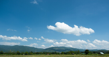 The white clouds have a quaint and rural shape. The sky is cloudy and blue