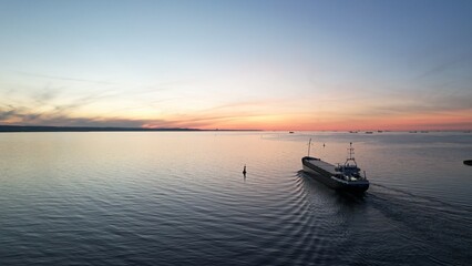 Naklejka premium Cargo ship on the background of the fiery sunset of the Baltic Sea.