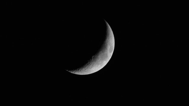 Quarter crescent moon, on a black background of the night. Lunar surface with craters.