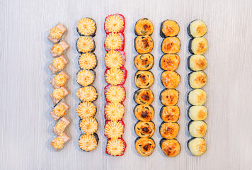 Top view set of different baked rolls on a light wooden background, selective focus, national Japanese food