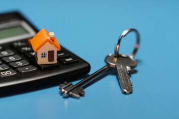 Toy house, keys and calculator. Real estate purchase concept.