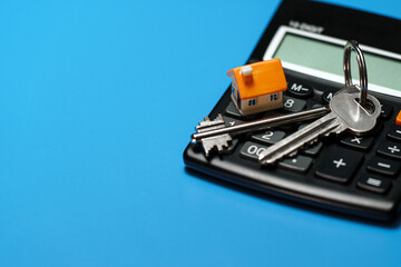 Toy house, keys and calculator. Real estate purchase concept.