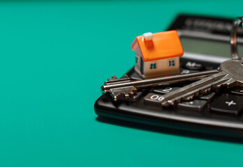 Toy house, keys and calculator. Real estate purchase concept.