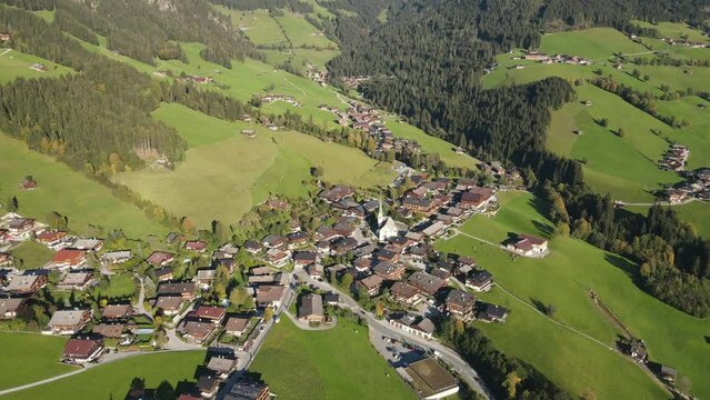 Down tilting aerial shot of the scenic mountain village Alpbach in Tyrol, Austria, in summer landscape surrounded by green meadows