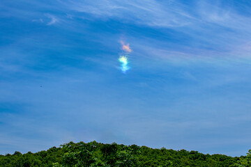 Obraz na płótnie Canvas A small Cloudbow forms on this bright Spring Afternoon. Sun shining thru clouds turns them into a rainbow.
