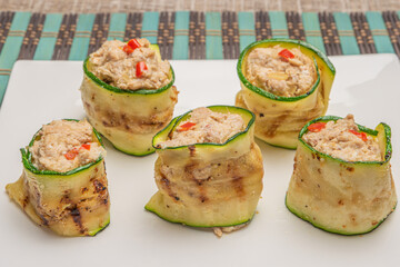 Grilled zucchini rolls with curd cheese and tuna on plate.