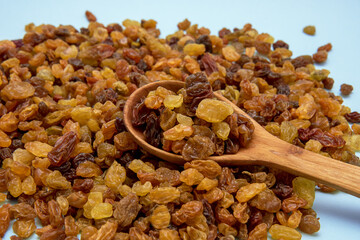 raisins close-up with a wooden spoon on a blue background