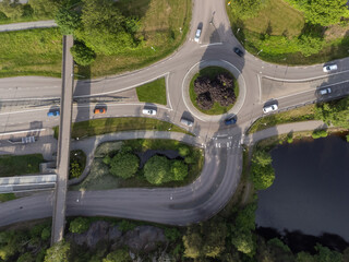 Bird's eye view of a traffic roundabout, roads, lanes with cars and a path. Aerial, drone photography taken from above in Sweden in summer.