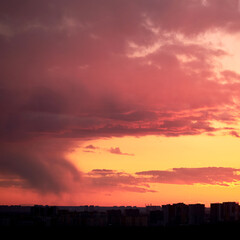 Dark clouds in the evening sunset sky with the setting sun. Dramatic sky during orange sunset
