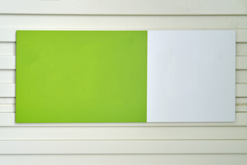 An empty sign in white and green colors on the wall of the building, mockup copy space