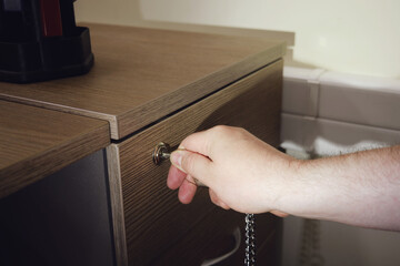 Man hand opens the office desk drawer, close up