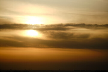 Evening dramatic sky with clouds during sunset. The sun sets behind dark clouds