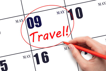 Hand drawing a red circle and writing the text TRAVEL on the calendar date 9 May. Travel planning.
