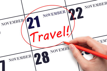 Hand drawing a red circle and writing the text TRAVEL on the calendar date 21 November. Travel planning.